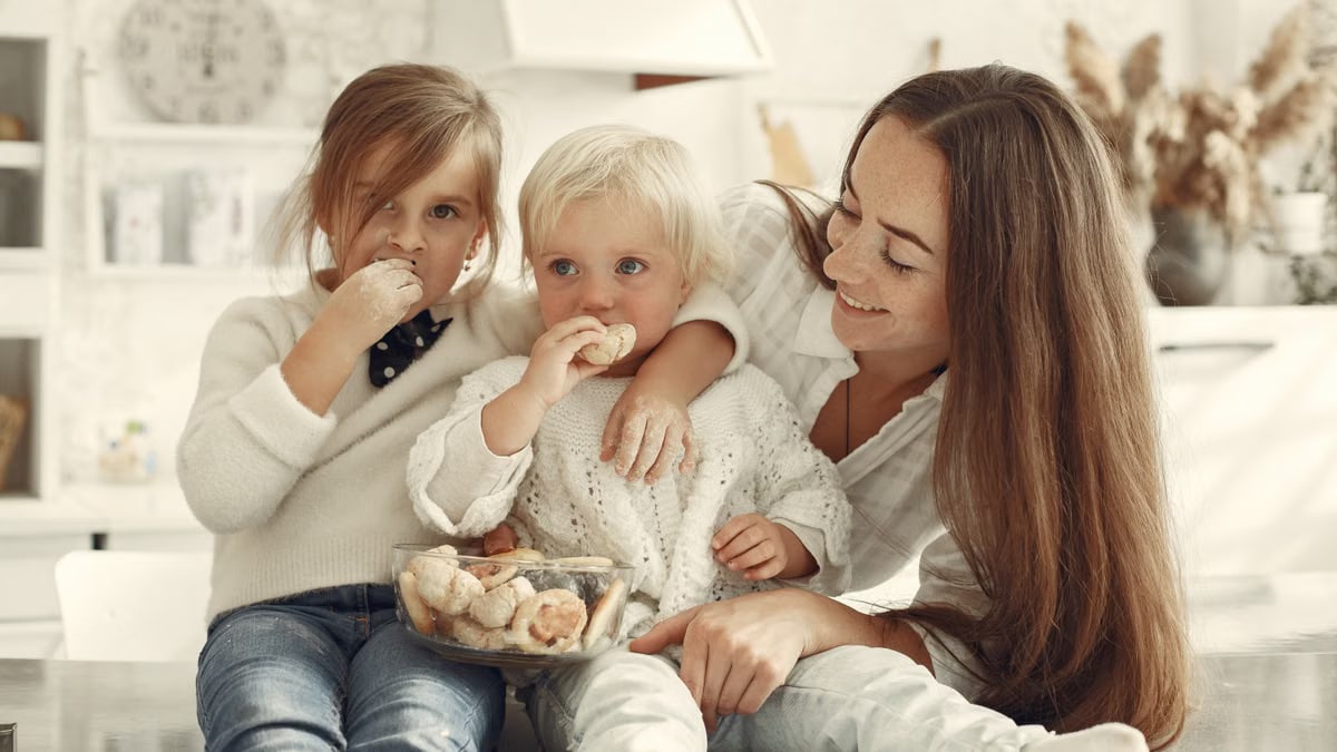 Mother and kids enjoying cookies in a warm, cozy kitchen setting.